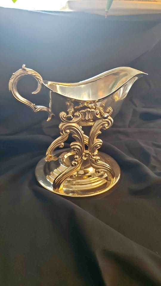 Ornate silver-plated gravy boat or sauce boat on pedestal stand