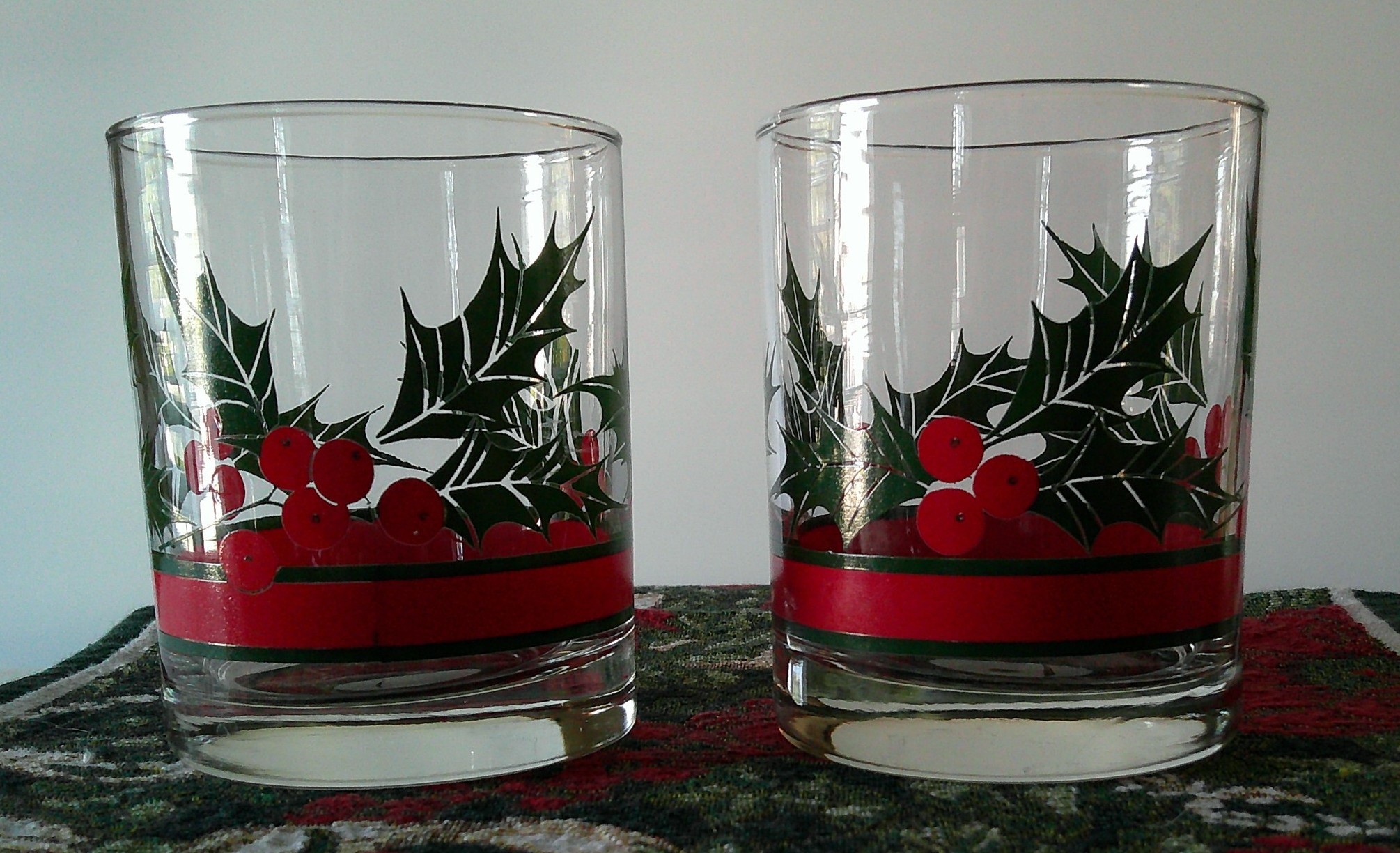 Pair of holiday-themed lowball/rocks glasses with holly and berry decoration
