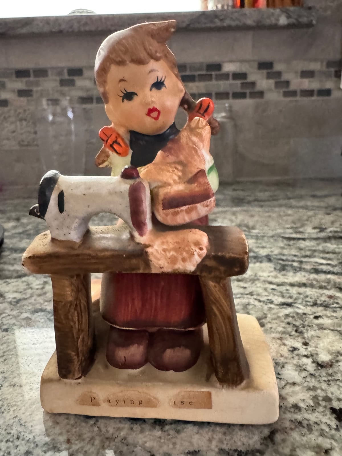 Ceramic figurine of a girl with dog on a bench (likely a decorative music box or novelty figurine)