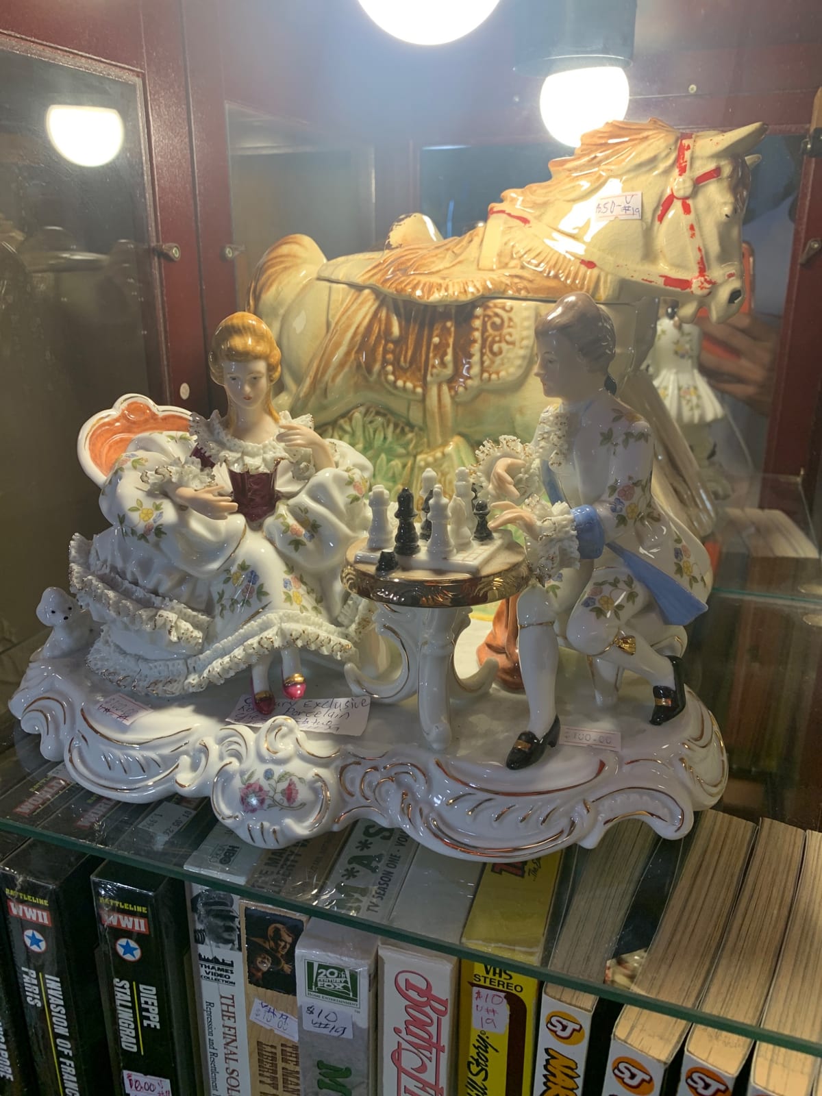 Porcelain figurine group with ladies playing chess beside a horse