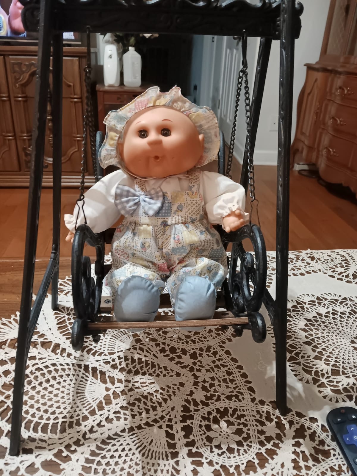 Vintage baby doll in a decorative metal swing