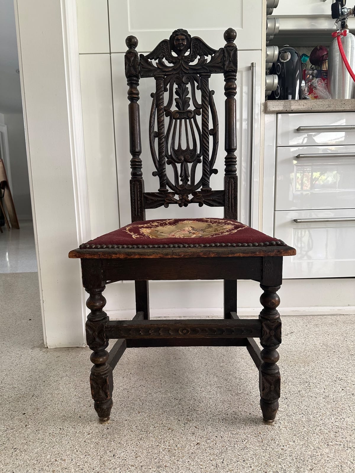 Carved oak side chair with upholstered seat and figural crest