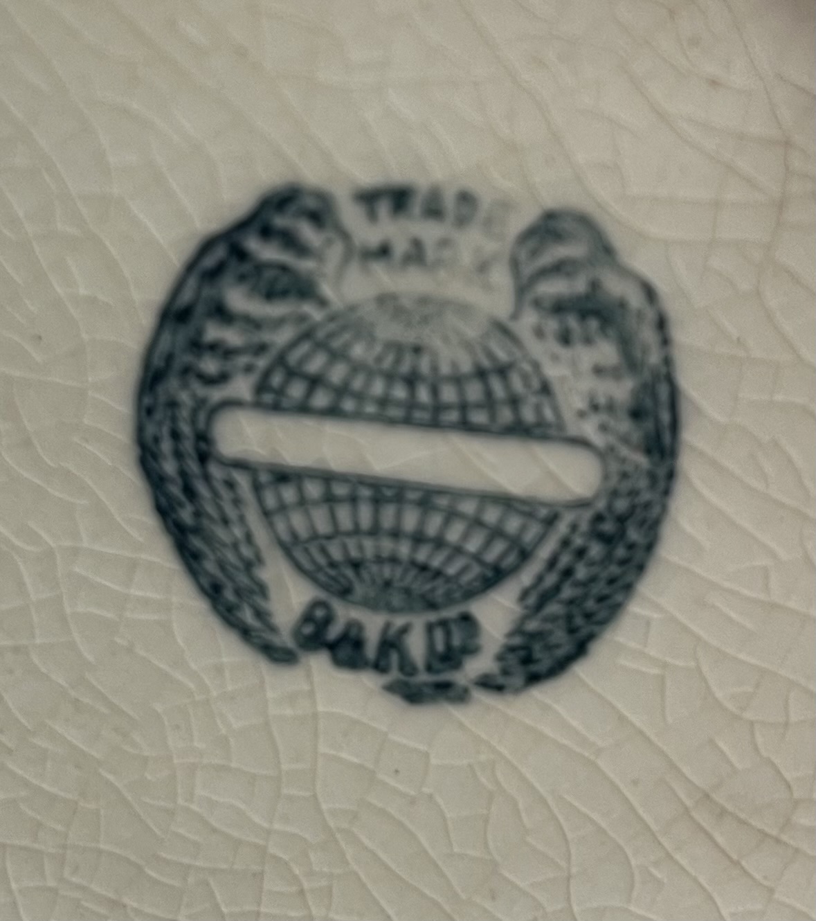 Ceramic maker's mark with winged globe emblem (likely transfer-printed pottery mark)