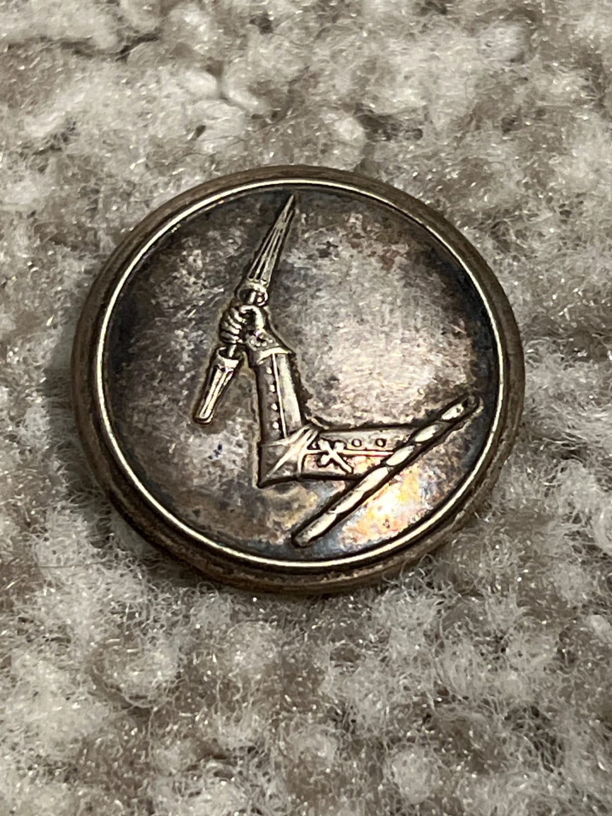 Decorative military-style uniform button or badge with crossed weapon motif