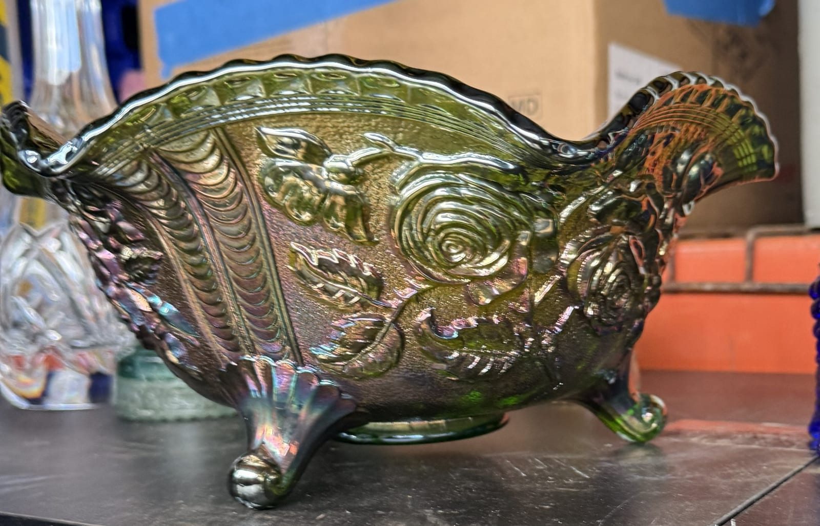 Iridescent carnival glass footed bowl with floral and scroll relief