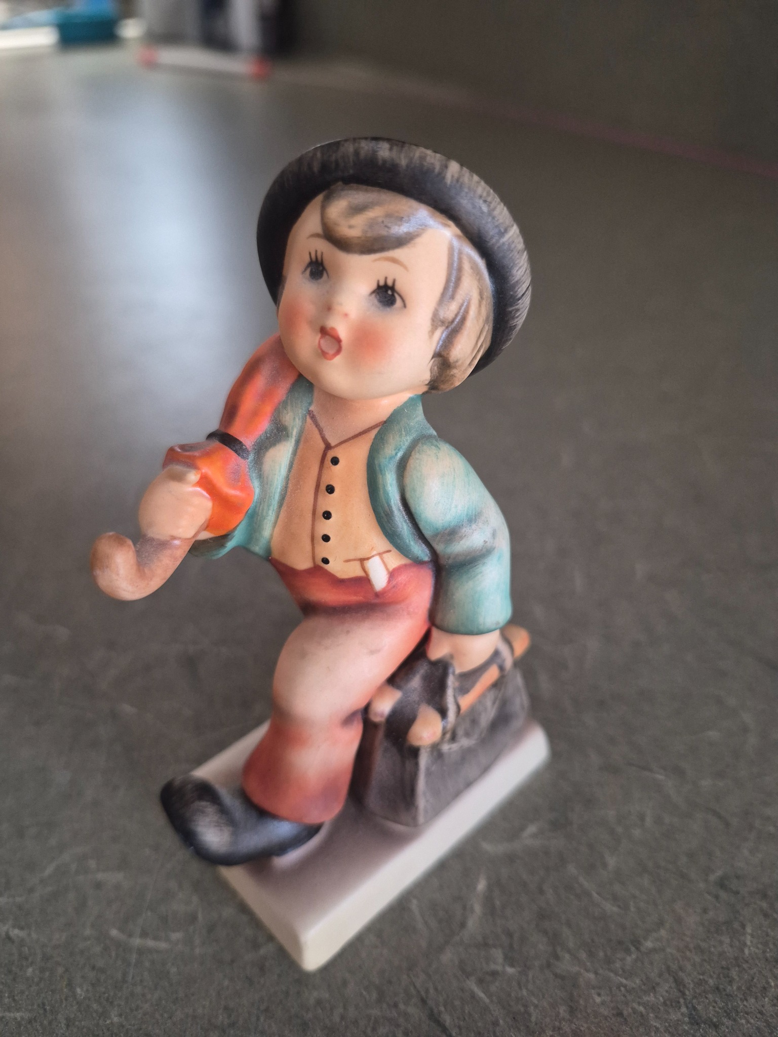 Hand-painted porcelain figurine of a boy with hat and satchel