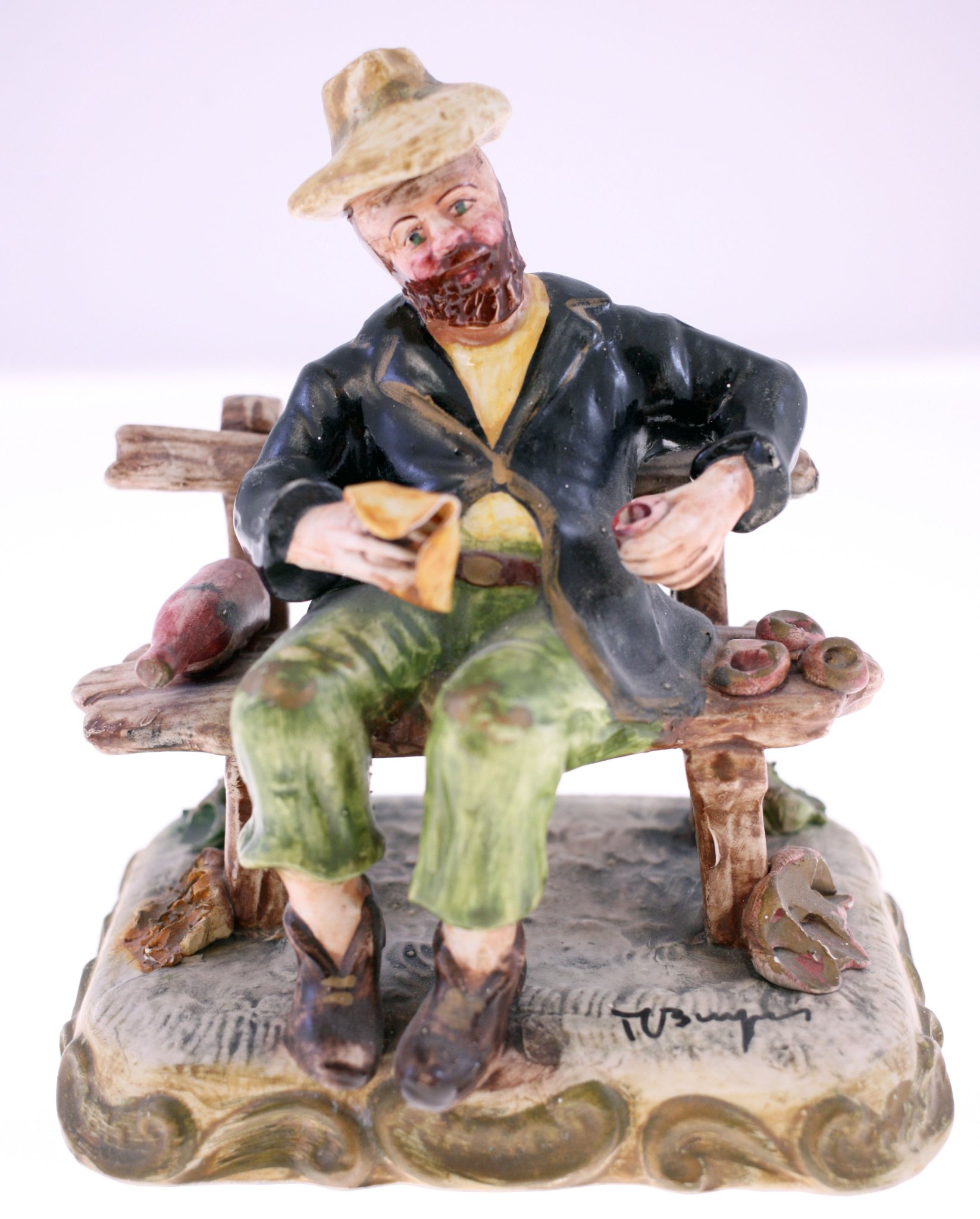 Hand-painted ceramic figurine of a seated peasant man on a bench