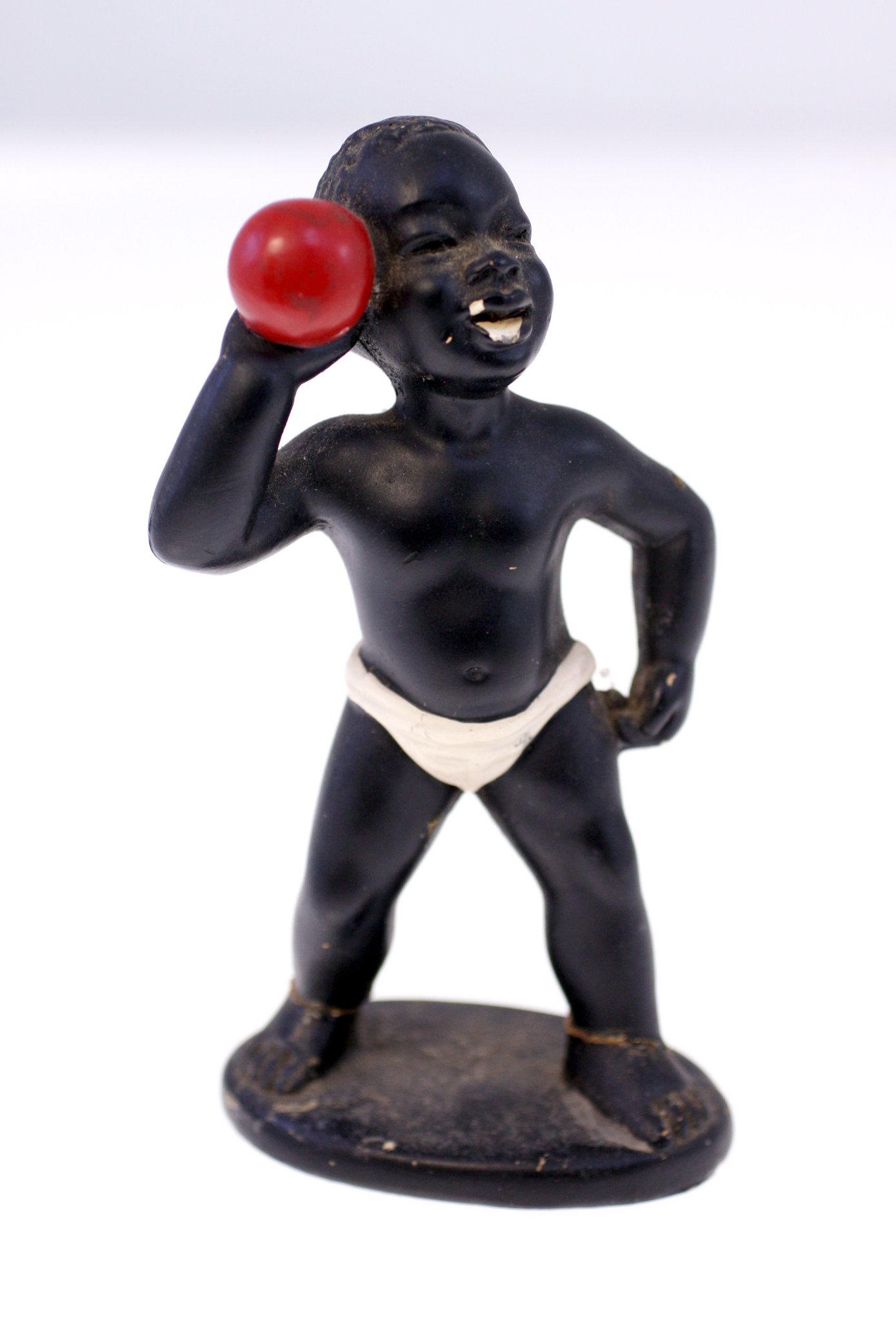 Small painted figurine of a child holding a red ball